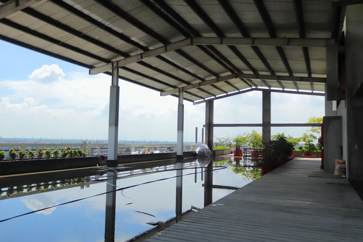 A covered rooftop terrace with a reflecting water channel under an open sky