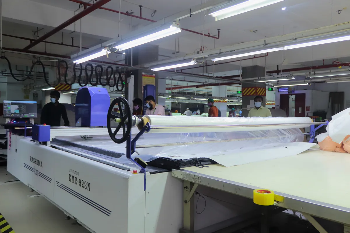 An automated fabric cutting table laid out with spread white fabric
