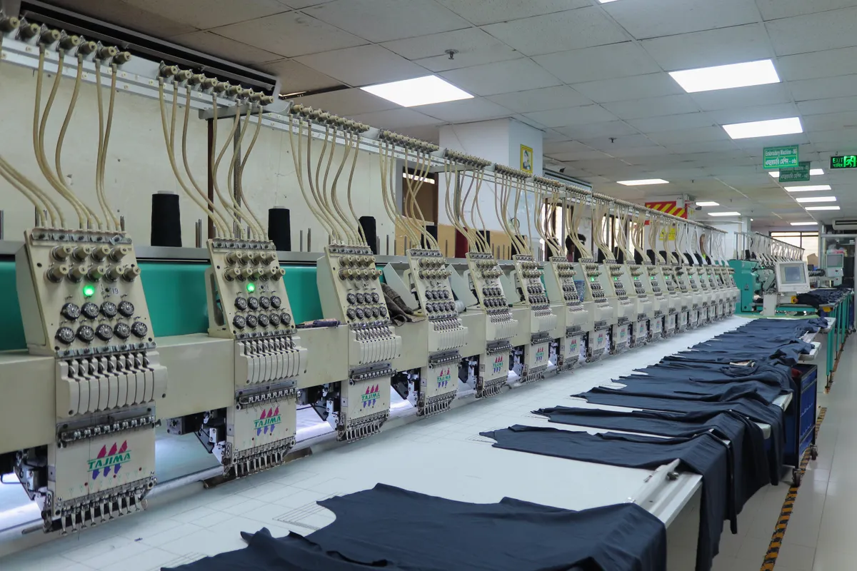 A row of multi head embroidery machines working over dark panels