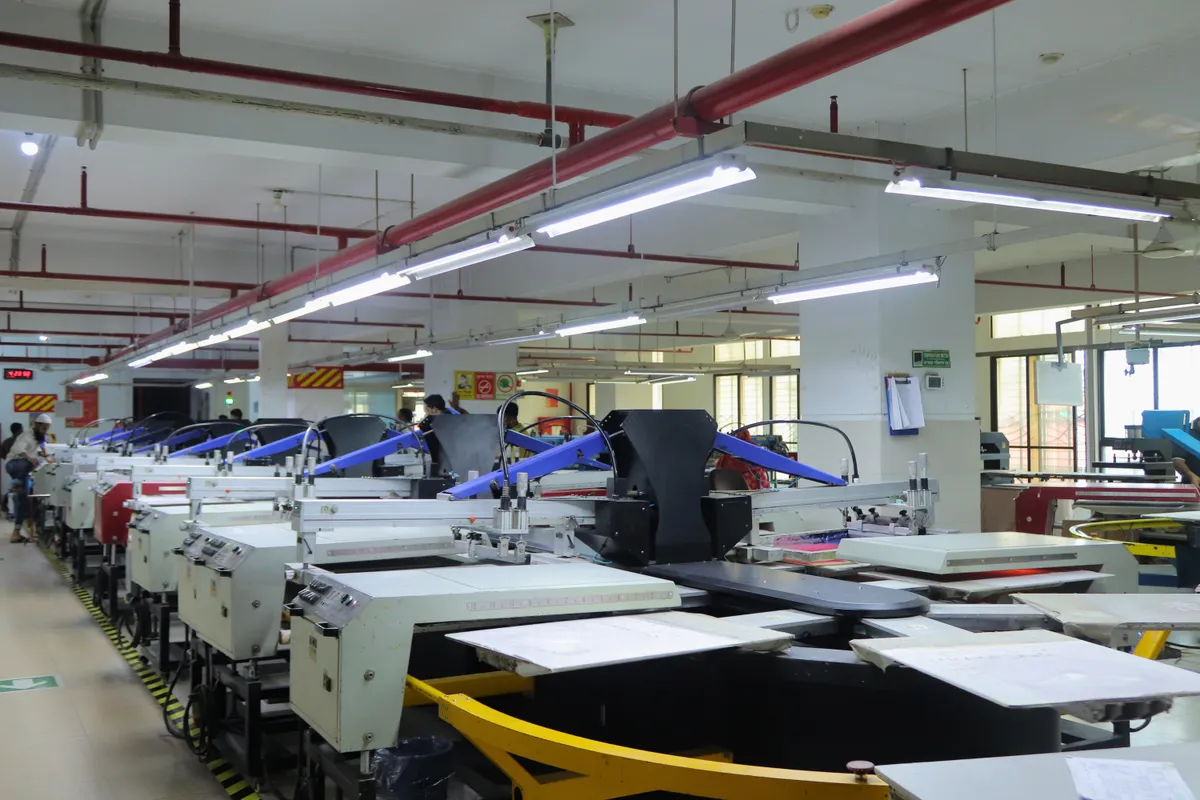 A wide screen-printing hall with a multi-station rotary carousel in the foreground