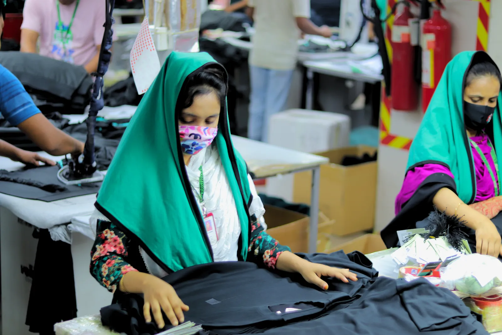 Two workers checking a garment at an inspection table